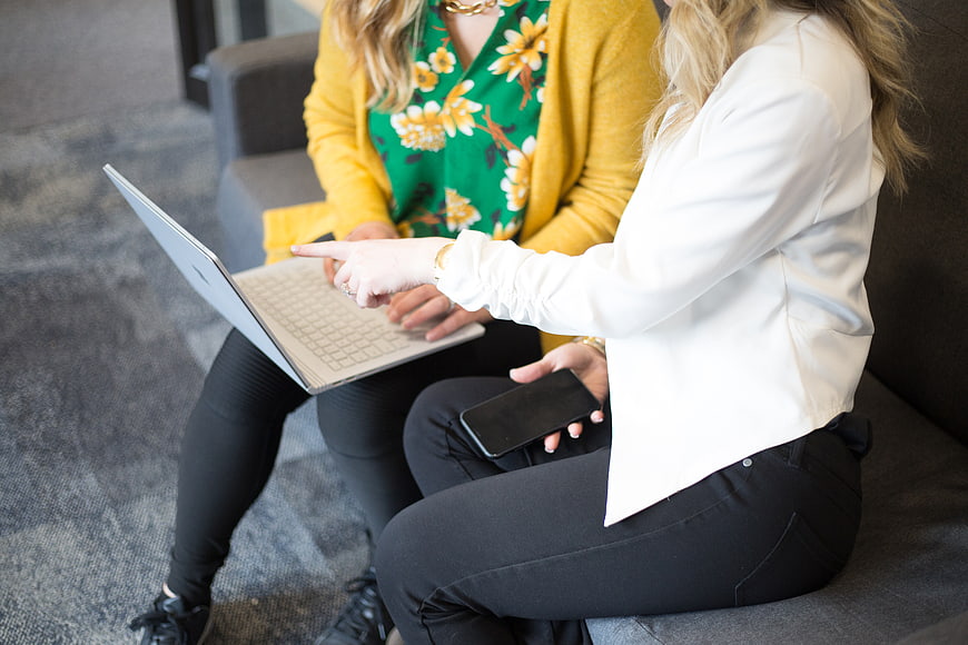Two women collaborating on laptop in office
