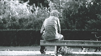 Lone figure in hoodie sitting on park bench