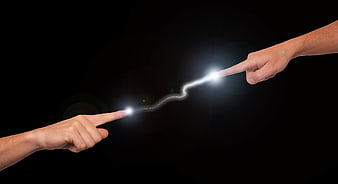 Two hands pointing with electric spark connection on black background