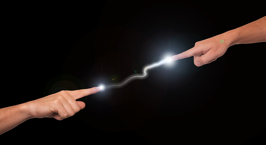Two hands pointing with electric spark connection on black background