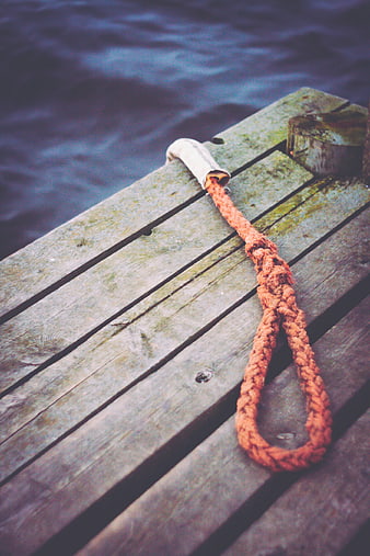 Orange mooring rope on weathered wooden dock