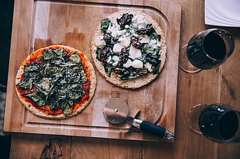 Top view of two rustic pizzas and red wine on wooden board