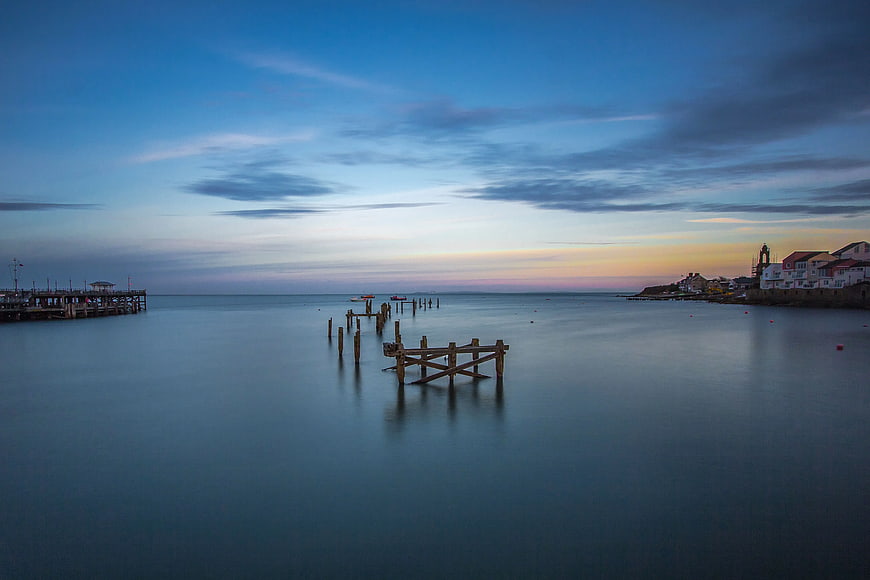 Serene Coastal Sunset with Wooden Pier and Smooth Water