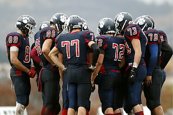 American football team huddle in navy blue uniforms