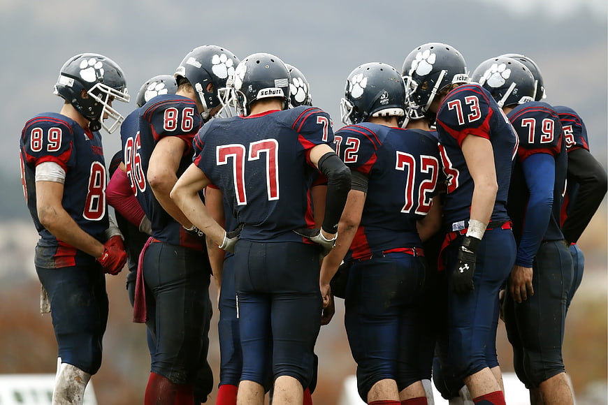 American football team huddle in navy blue uniforms