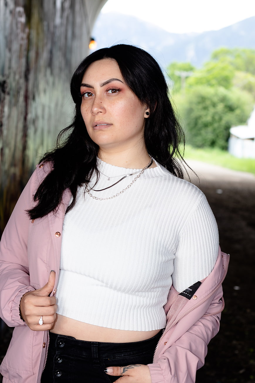 Portrait of woman with black hair in pink jacket outdoors