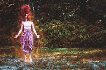 Mystical woman jumping in forest with fire effects
