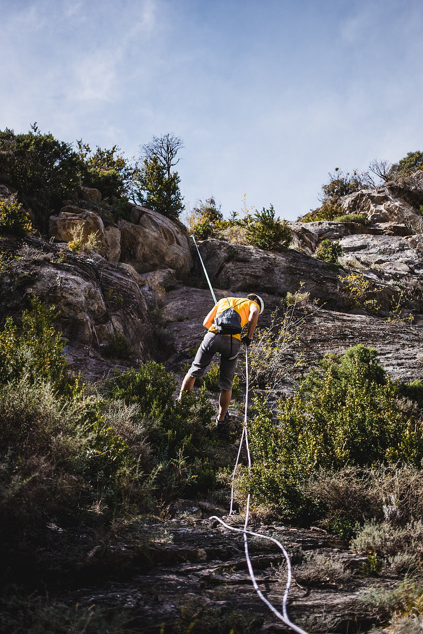 Man rappelling down rocky cliff with rope