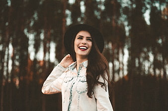 Happy woman in hat laughing in forest