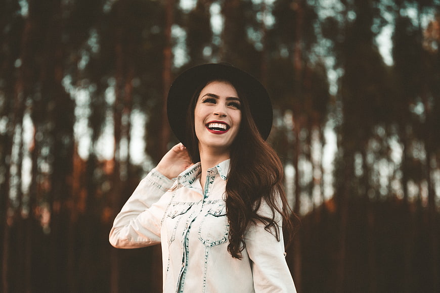 Happy woman in hat laughing in forest