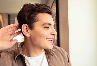 Young man smiling with hand cupped behind ear
