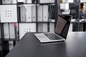 Silver laptop on black desk in modern office workspace