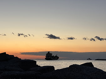 Cargo ship silhouette on ocean horizon at sunset