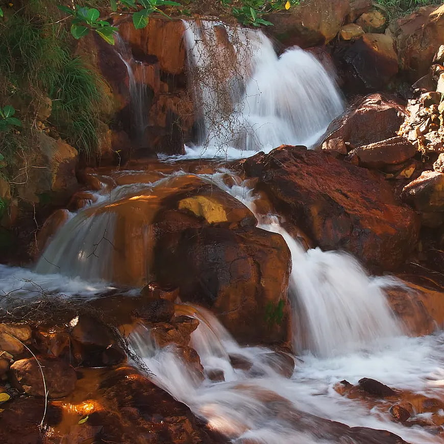 Serene waterfall cascading over reddish rocks in a forest