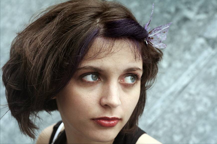 Close-up portrait of woman with purple streak and butterfly hair clip