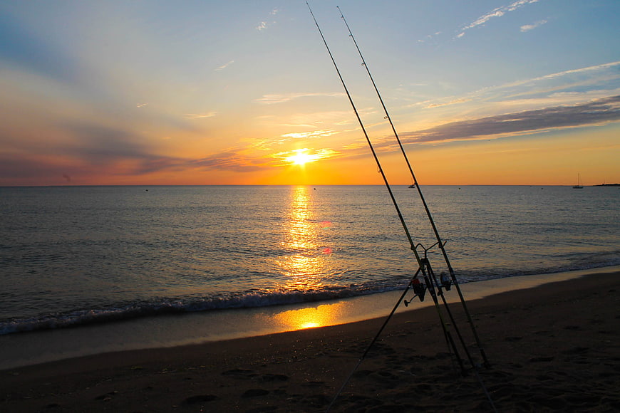 Fishing Rods on Beach at Sunset with Golden Horizon