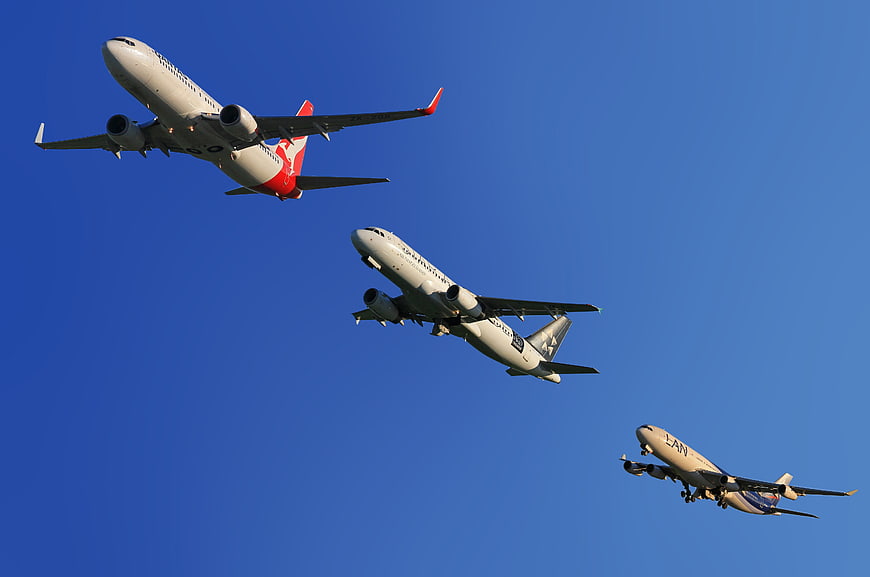 Three Commercial Airplanes Taking Off Against Blue Sky
