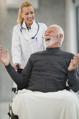 Happy Senior Man in Wheelchair Laughing with Female Doctor