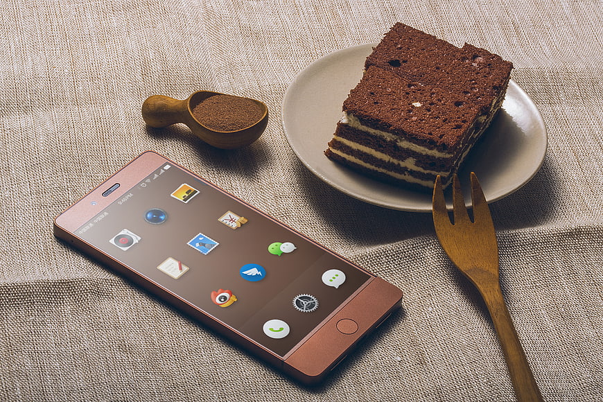 Rose Gold Smartphone Next to Chocolate Cake Slice on Linen