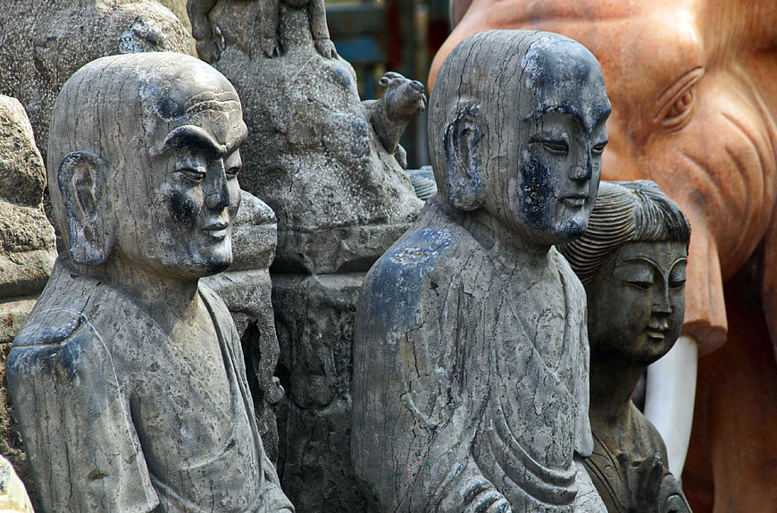 Close-up of weathered stone Buddhist monk statues