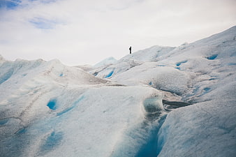 Lone Hiker Standing on Blue Glacier Ice Landscape