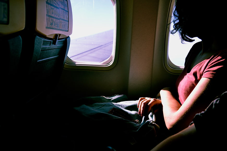 Woman sitting by airplane window looking out at wing