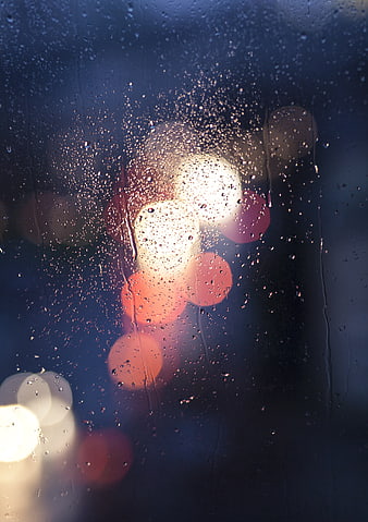 Raindrops on Glass with Blurred Bokeh Lights at Night