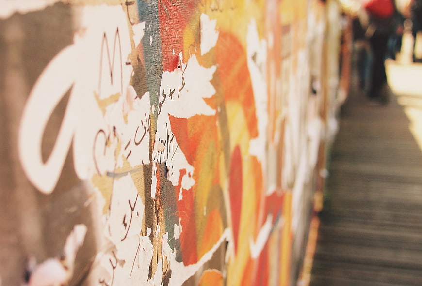 Close-up of textured graffiti wall with peeling paint and urban street art