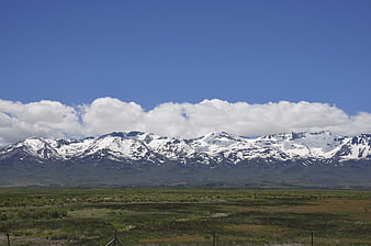 Snow-capped mountain range with green valley and blue sky