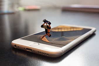 Miniature skateboarder popping out of smartphone screen