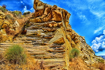 Dramatic layered rock formation against vibrant blue sky