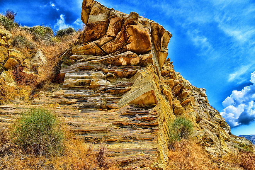 Dramatic layered rock formation against vibrant blue sky