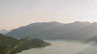 Serene mountain lake landscape with sun rays and forest