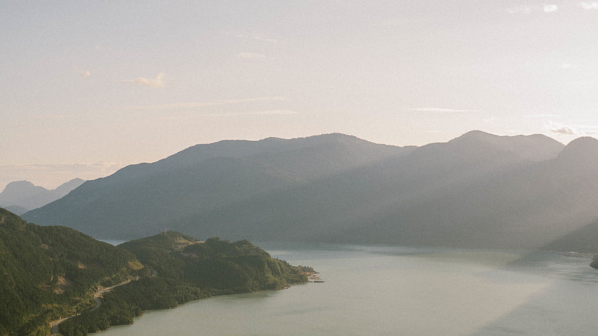 Serene mountain lake landscape with sun rays and forest