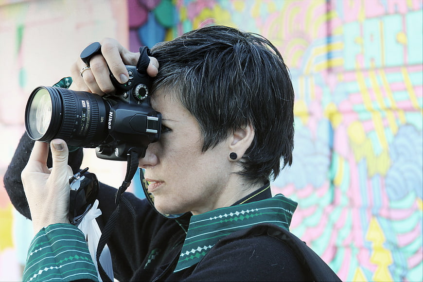 Woman Photographer with DSLR Camera Against Graffiti Wall