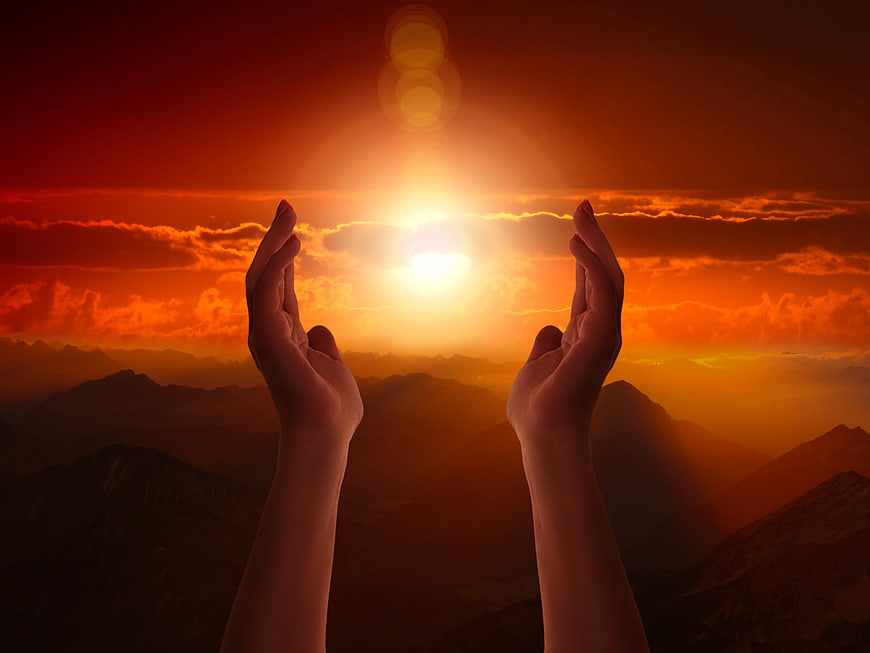 Praying Hands Silhouette Against Dramatic Orange Mountain Sunset