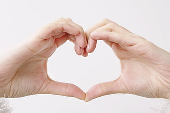 Hands forming heart shape on white background