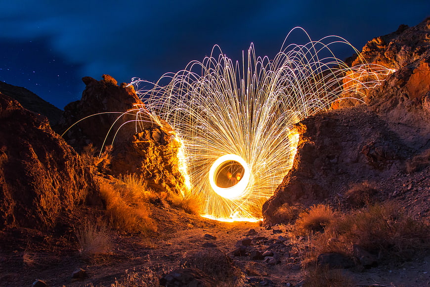 Steel wool photography creating a glowing light trail in a rocky canyon at night