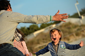 Joyful child laughing with arms outstretched at the beach