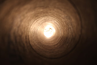 Abstract view inside a wooden tube with bright light at the end
