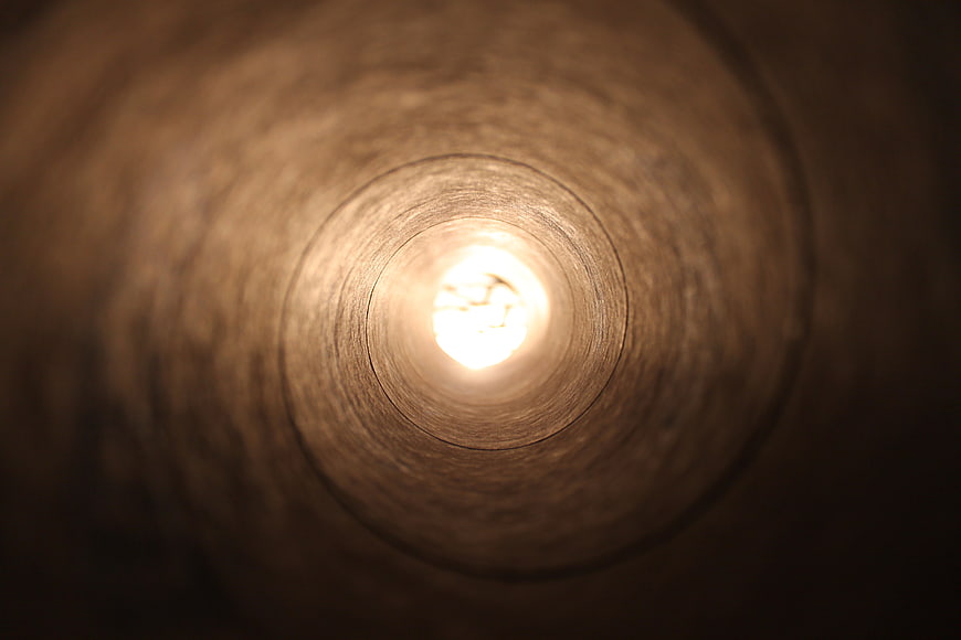 Abstract view inside a wooden tube with bright light at the end