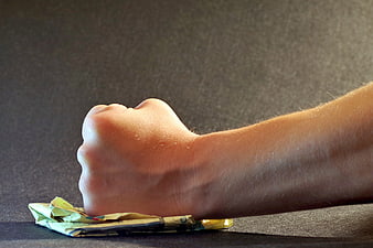 Fist Crushing Crumpled Paper on Dark Fabric Background