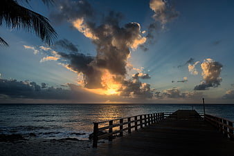 Dramatic Sunset Over Ocean Pier with Sun Rays