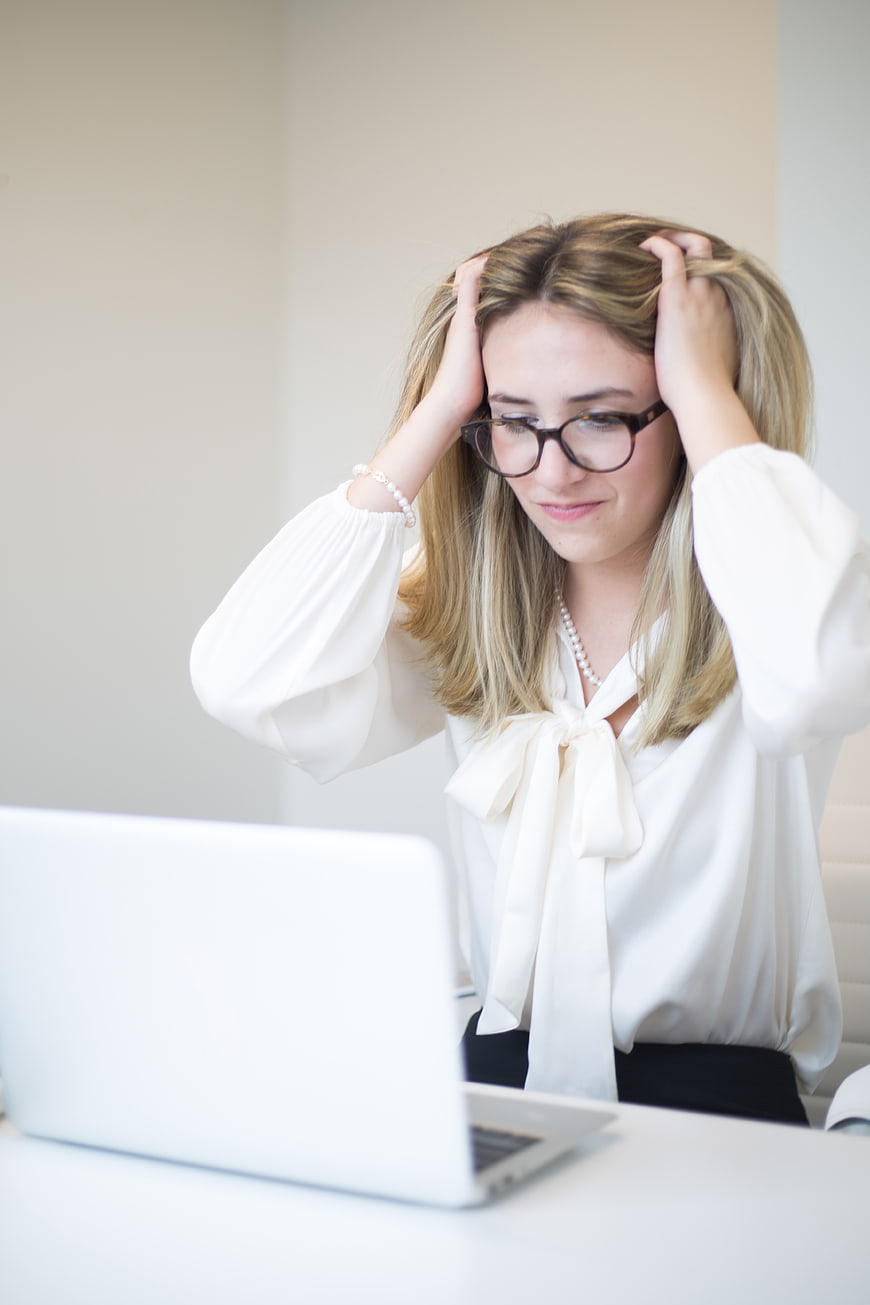 Stressed Businesswoman Holding Head at Laptop