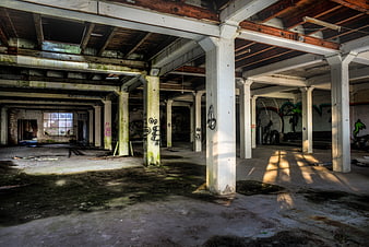 Abandoned industrial warehouse interior with graffiti and sunlight