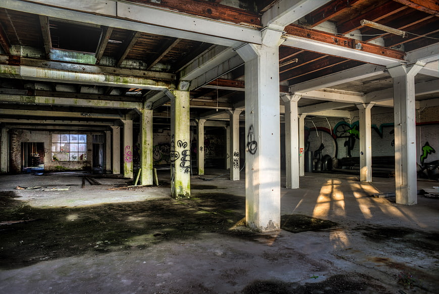 Abandoned industrial warehouse interior with graffiti and sunlight