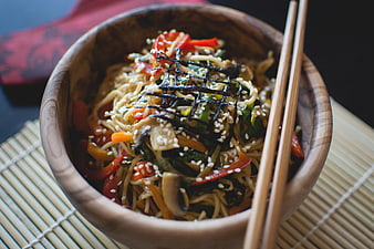 Asian noodle salad in wooden bowl with chopsticks