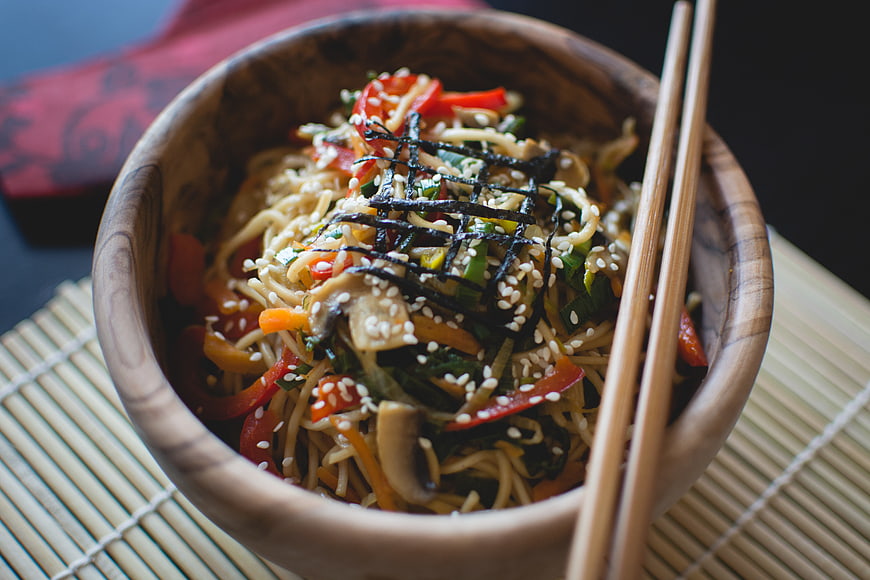 Asian noodle salad in wooden bowl with chopsticks