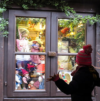 Child admiring vintage dolls in a festive shop window