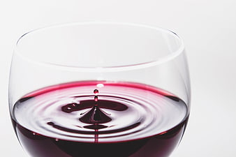 Red wine droplet splash in a clear glass on a white background